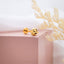 a pair of earrings sitting on top of a pink box