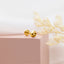 a pair of gold earrings sitting on top of a pink box