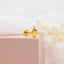 a pair of yellow gold earrings on a pink box