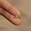 a person&#39;s hand holding a tiny gold ring