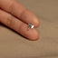 a person&#39;s hand holding a tiny silver ring