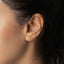 a close up of a woman&#39;s ear wearing a gold earring