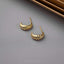 a pair of gold earrings sitting on top of a table