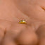 a close up of a person&#39;s hand holding a tiny gold object