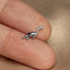 a small silver dinosaur brooch sitting on top of a person&#39;s finger