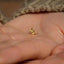 a person&#39;s hand holding a tiny gold ring