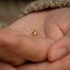 a person holding a tiny gold object in their hand