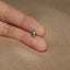 a person&#39;s hand holding a tiny silver ring