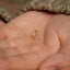 a person holding a tiny gold ring in their hand