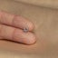 a person&#39;s hand holding a small diamond ring