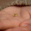 a tiny gold cat earring on someone&#39;s hand